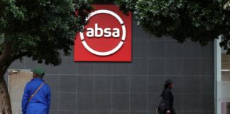 Absa bank logo on a building in Cape Town, South Africa, with a person walking by.
